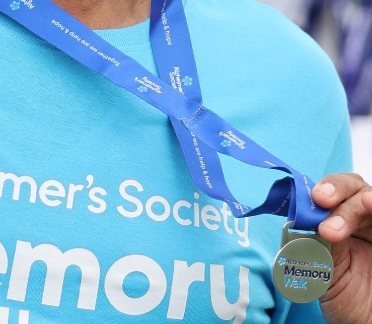 Two happy young people wearing memory walk t-shirts holding a ball
