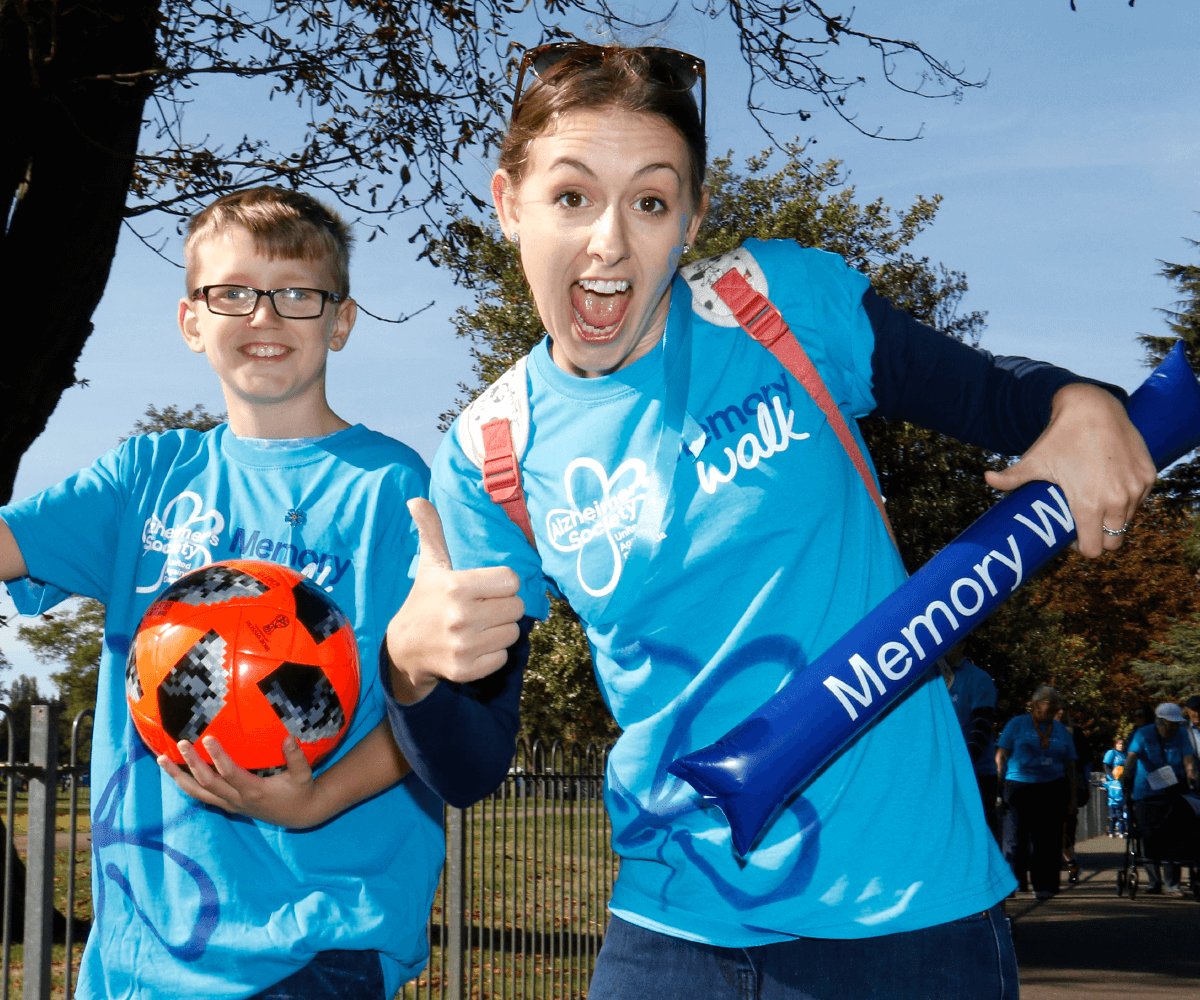 Two happy young people wearing memory walk t-shirts holding a ball
