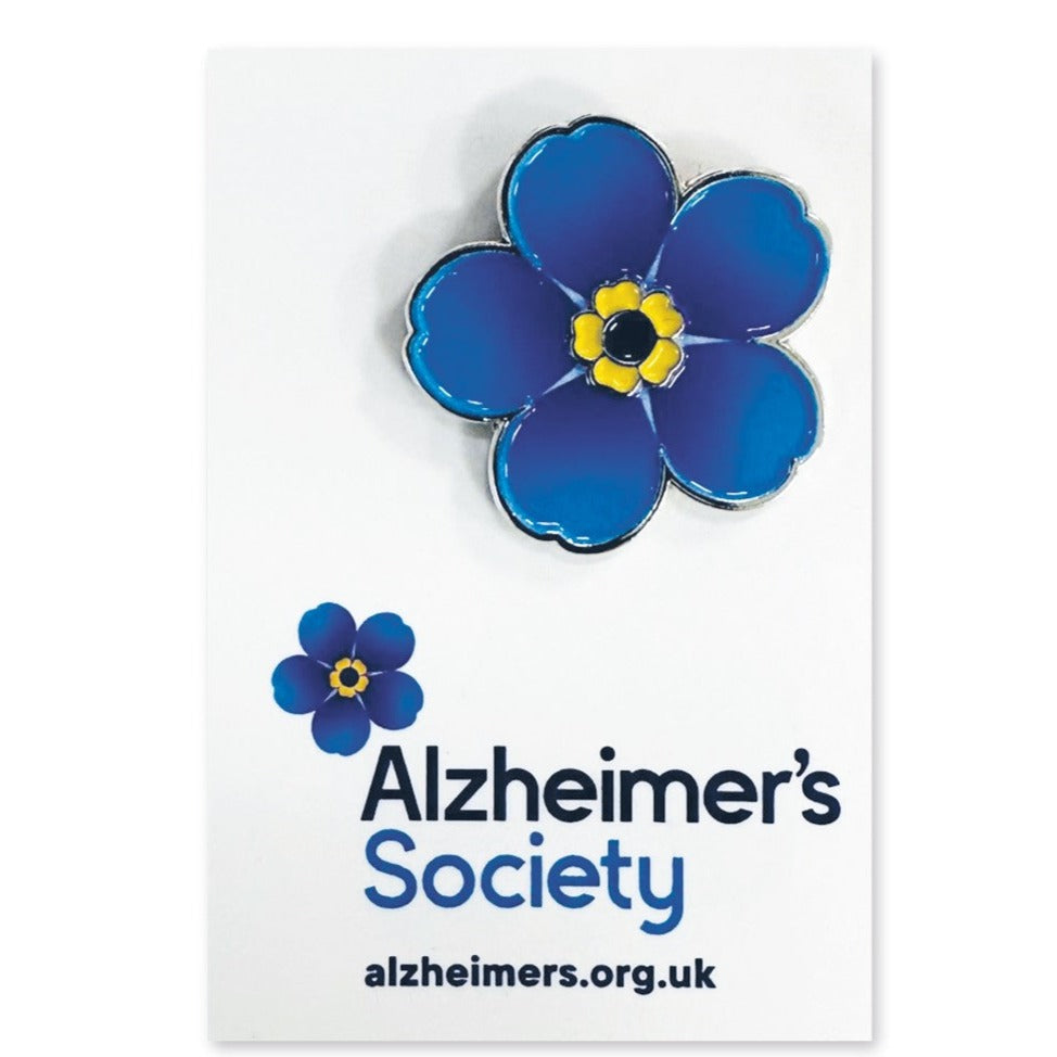 A 25 mm metal base enamel badge with butterfly fastening in the shape of a 2D forget-me-not flower.  The flower has 5 bright, sky blue petals with a yellow and black centre.  The badge comes on a backing card with the Alzheimer's Society logo