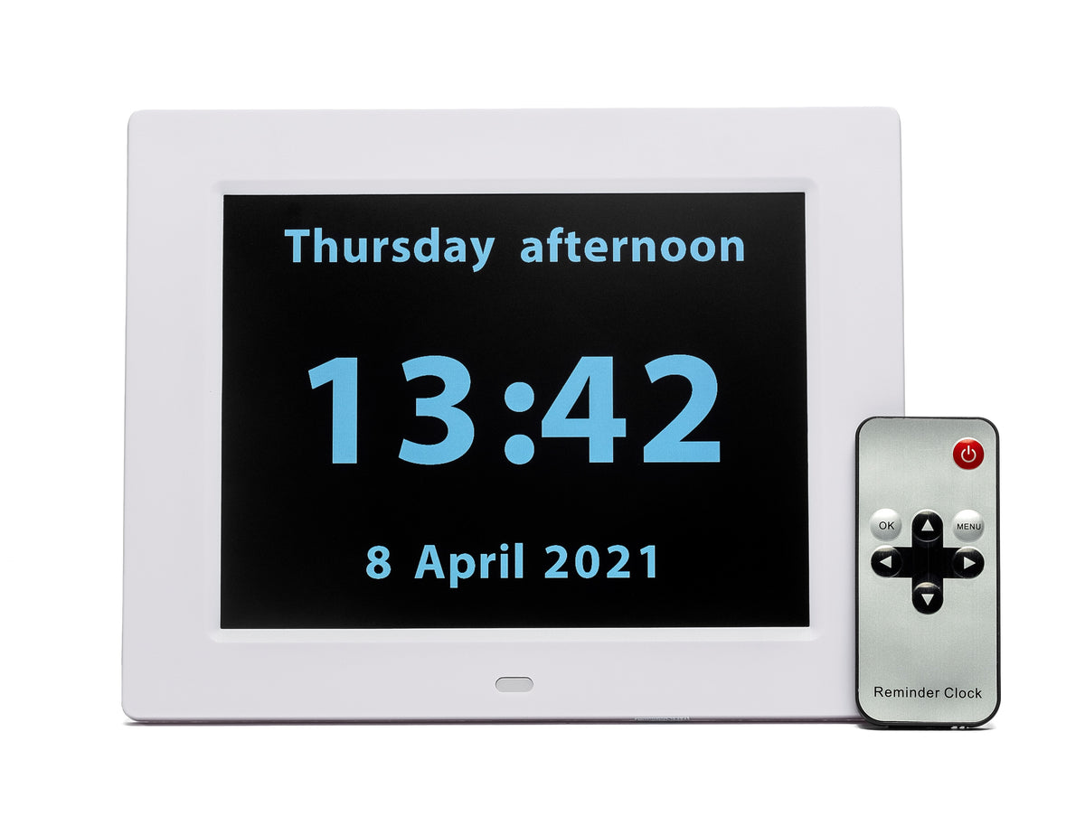 The clock has a thick white border and black screen which displays the day, time, date and year in clear pale blue alphanumeric digital display.  Across the top of the screen the text reads&#39;Thursday afternoon&#39;. Across the bottom of the screen, in the same font, the text reads &#39;8 April 2021&#39;.  In the middle of the screen the time is given in large 24-hour clock numbers. 