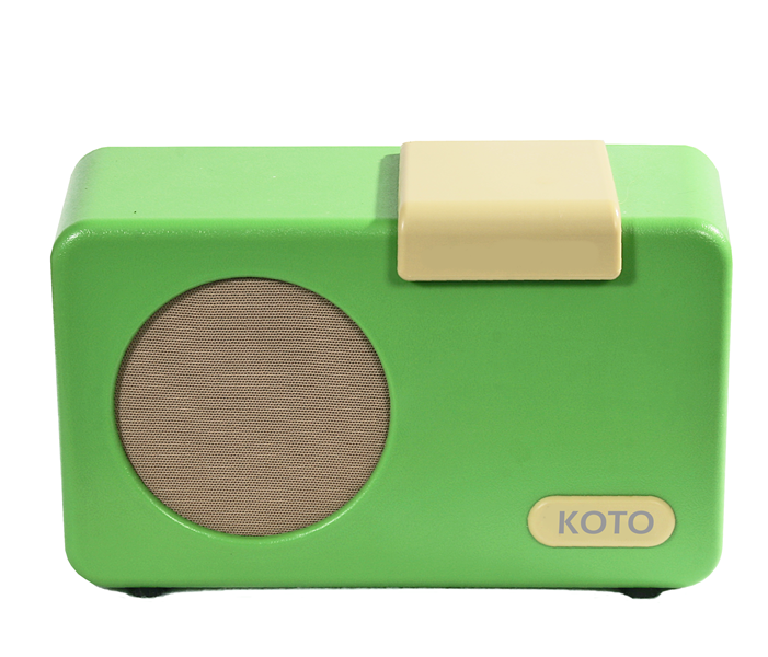 A bright green, rectangular music player, with one large, rectangular cream-coloured button that sits proud on the top right of the player.  The button&#39;s depth is visible from the front. On the front left of the player there is a large, round, beige flat speaker panel.  In the bottom right, hand front corner there is a small, cream oblong displaying the word KOTO. The player sits on two integrated low feet.