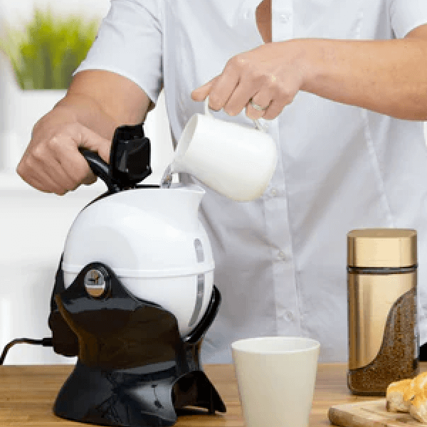A person pouring water into an assistive kettle