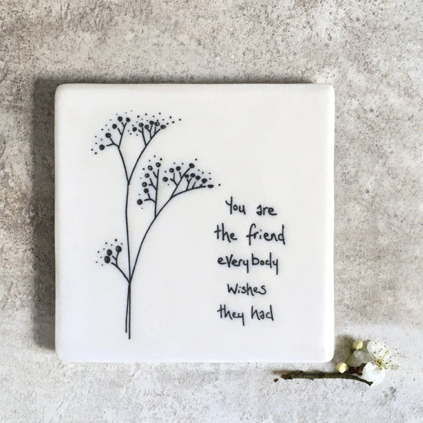 A square coaster with flower design and message &#39;you are the friend everyone wishes they had&#39; and real flower in the photo.