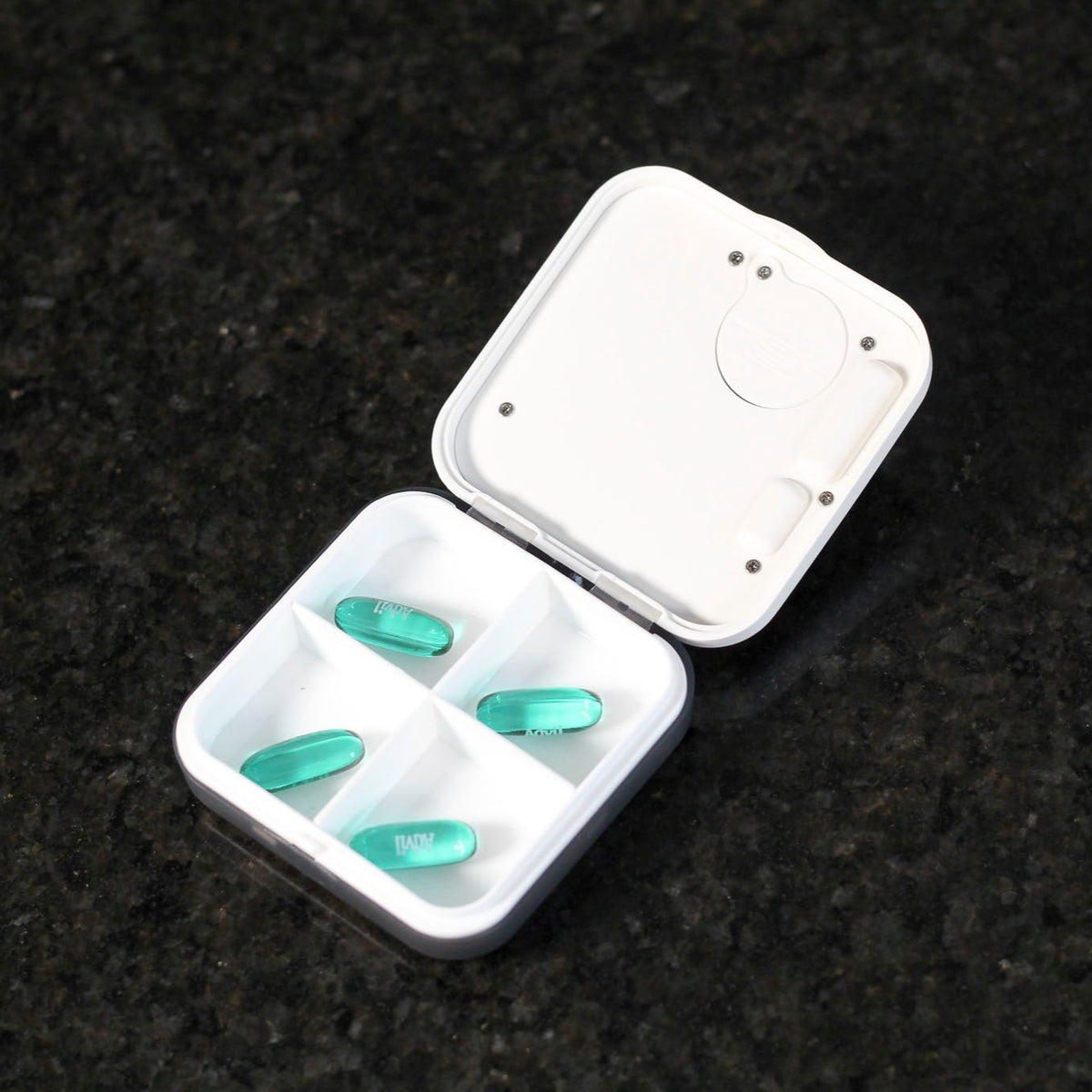 Inside of a pill timer box - 4 compartments featuring dummy tablets