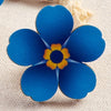 Blue flower with a yellow center on a textured background as a pin badge
