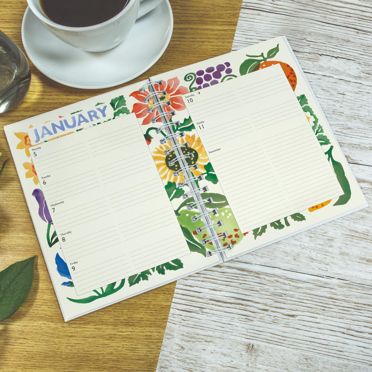 Floral-themed calendar pad on a wooden table with a cup of coffee.