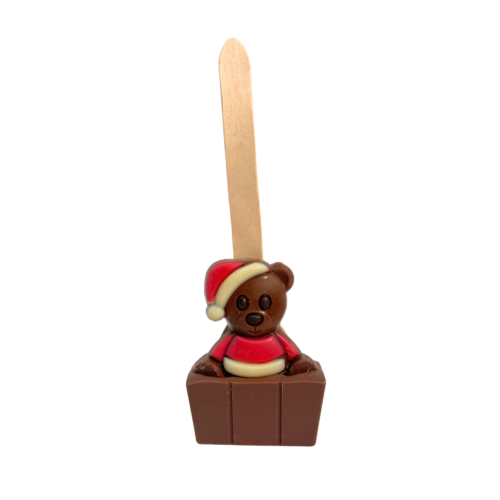 A small chocolate cube with a brown chocolate teddy bear figure wearing a red and cream Santa hat and sweater. A tall wooden spoon sticks out above it, on a plain white background.