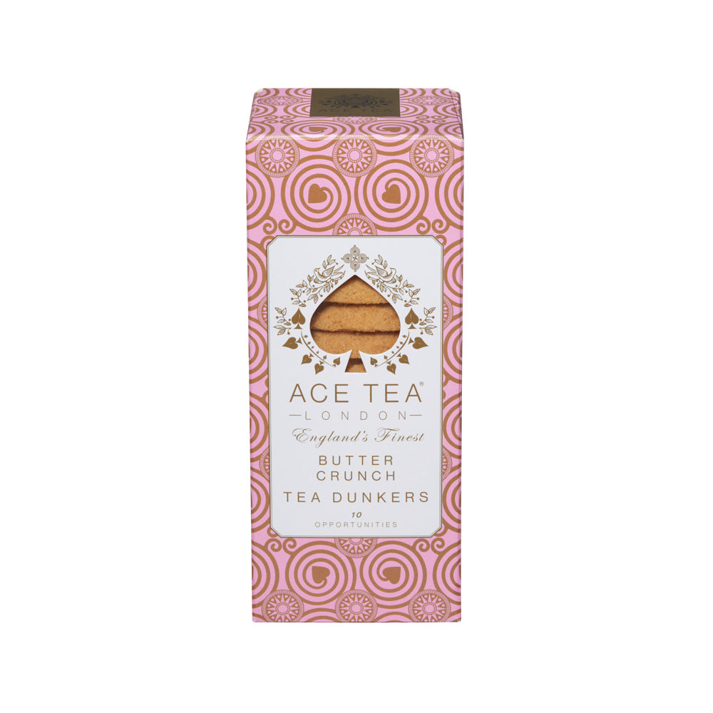 A boxed food product on a plain white background. The package is a tall rectangular carton with pink ornamental swirl patterns, a white central label, and a clear window showing tan butter crunch cookies.