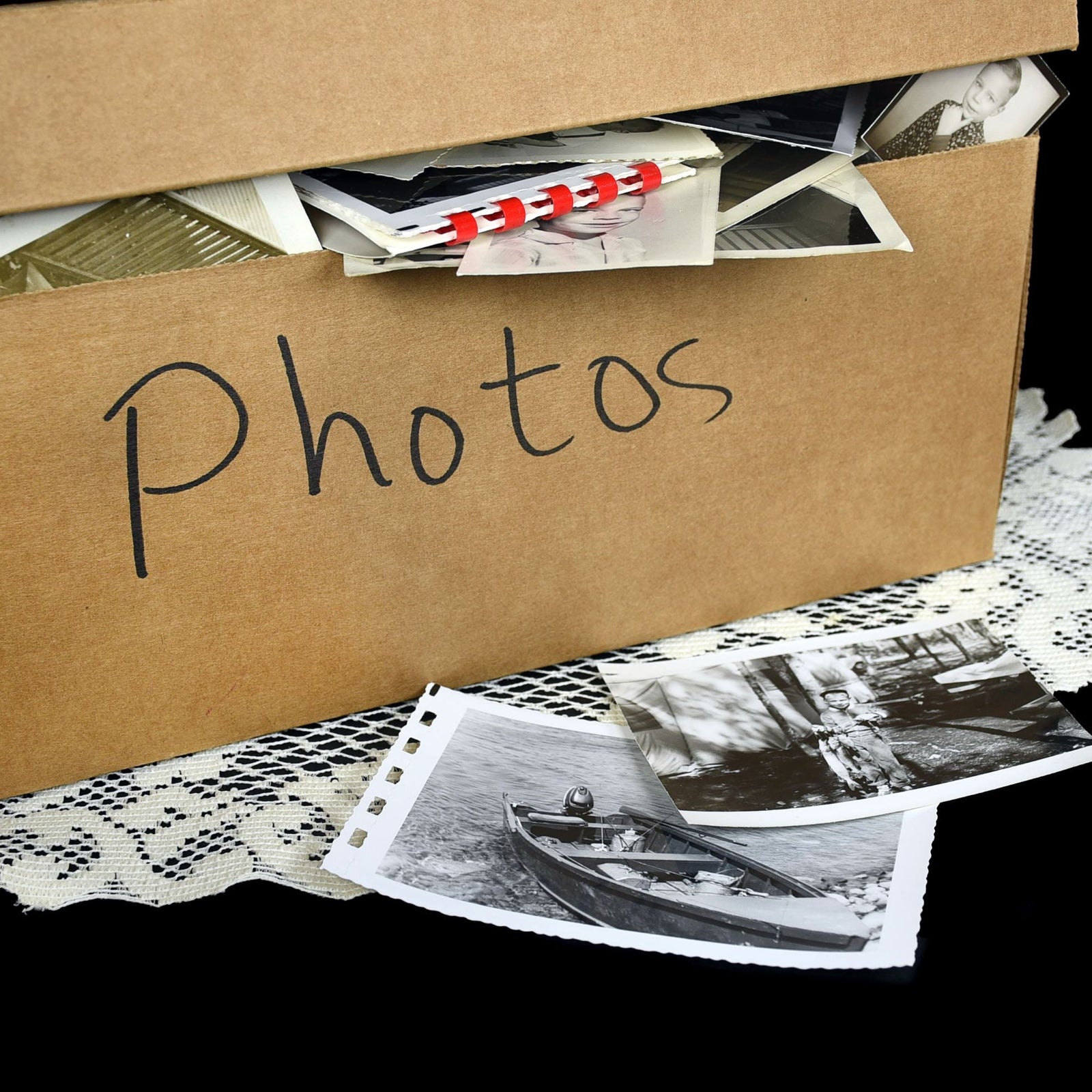 Cardboard box labeled 'Photos' with vintage photographs on a black background