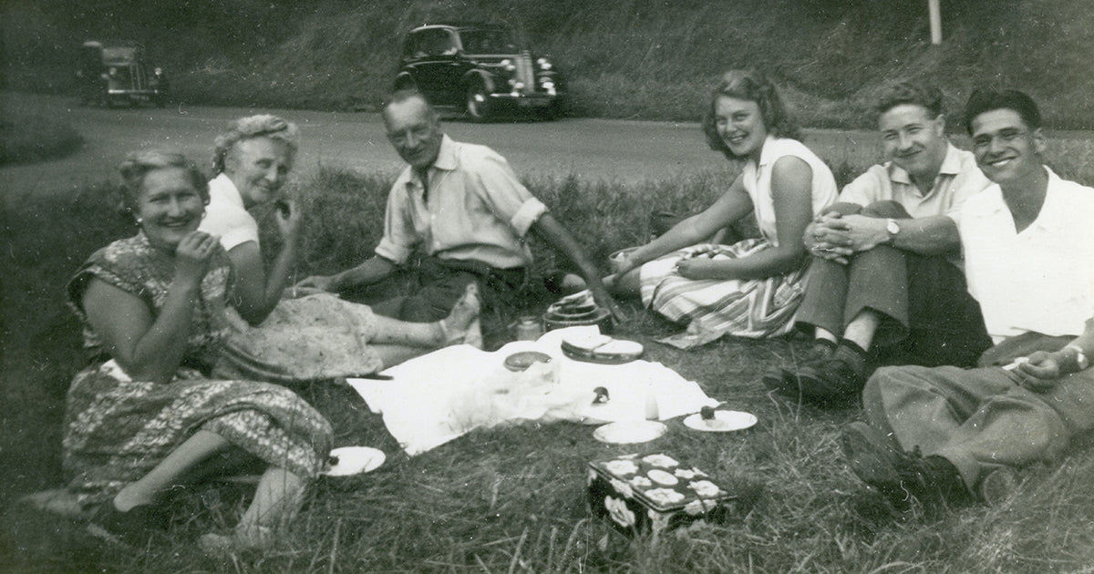 Vintage black and white photo of a group of people having a picnic outdoors.