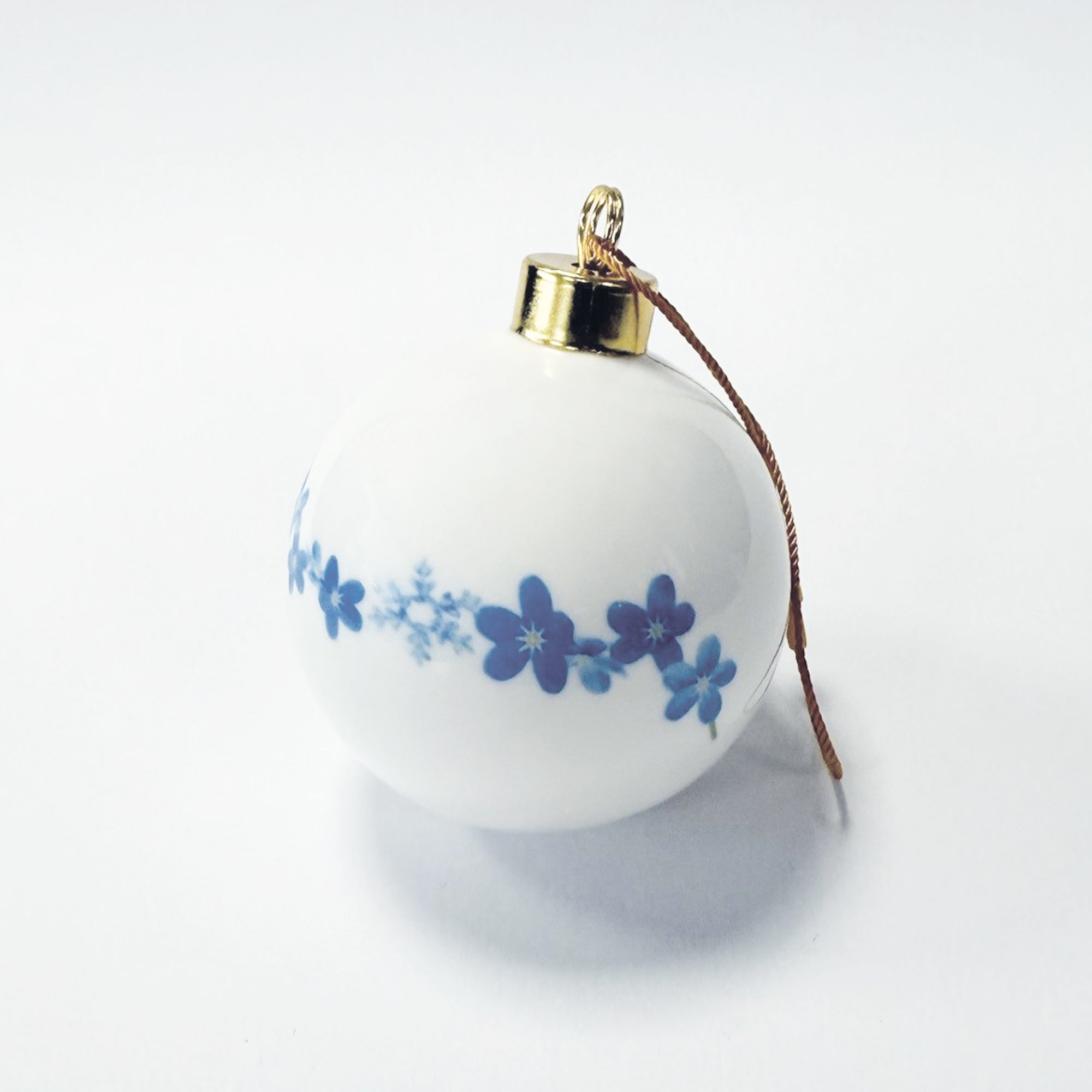 Decorative Christmas ball ornament with blue forget-me-not and snowflake pattern on a white background.