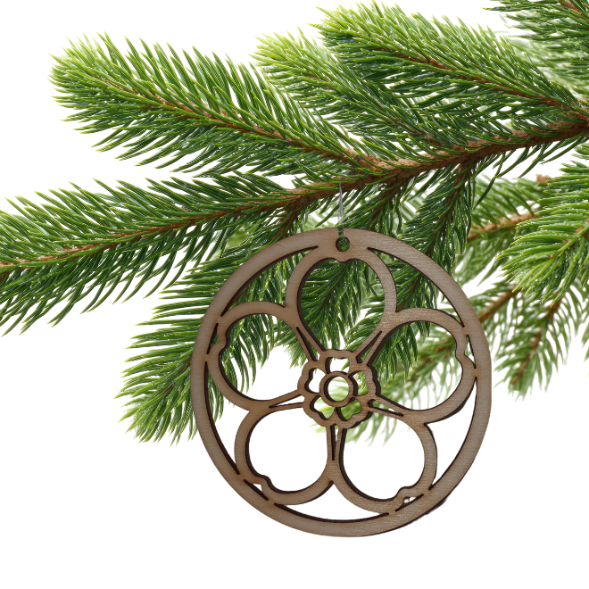 Wooden cut out forget-me-not decoration hanging from a fir tree branch.