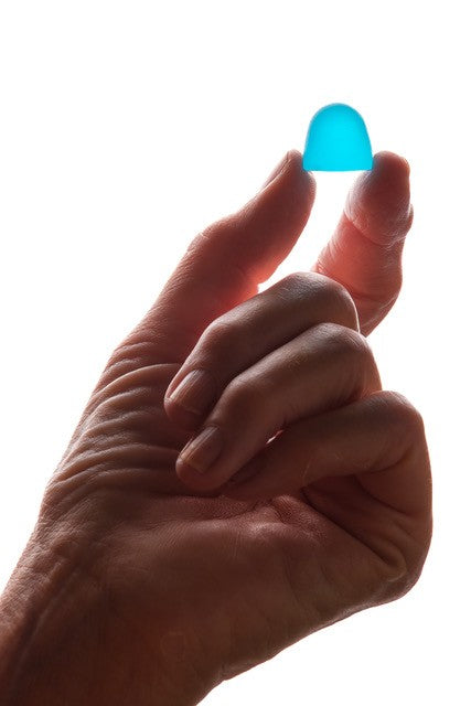 One blue gummy sweet being held by a hand.