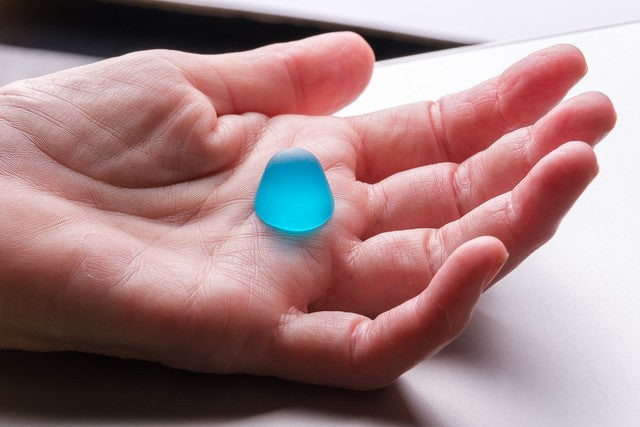 One blue gummy sweet being held by a hand.