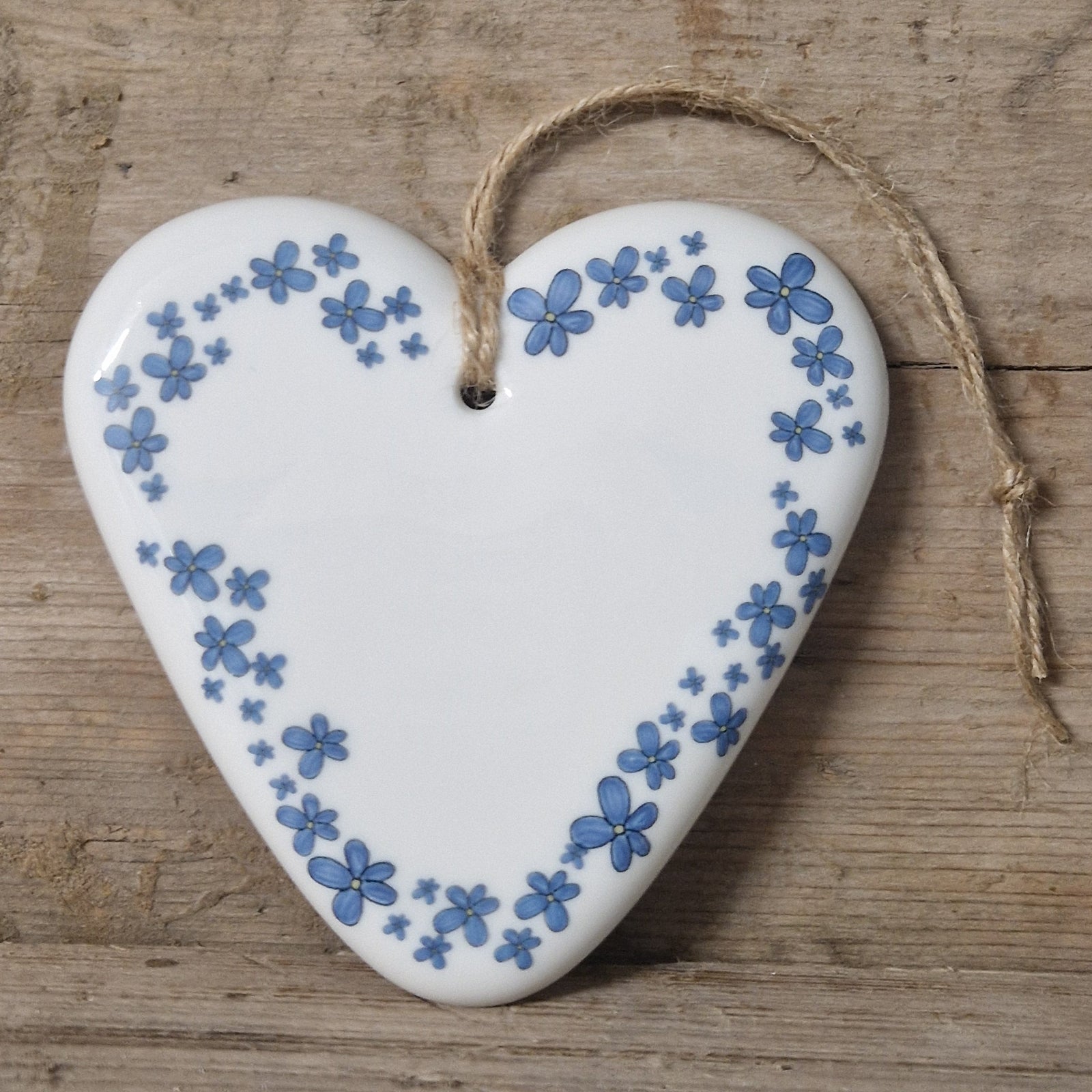 Heart-shaped ceramic ornament with floral pattern on a wooden surface
