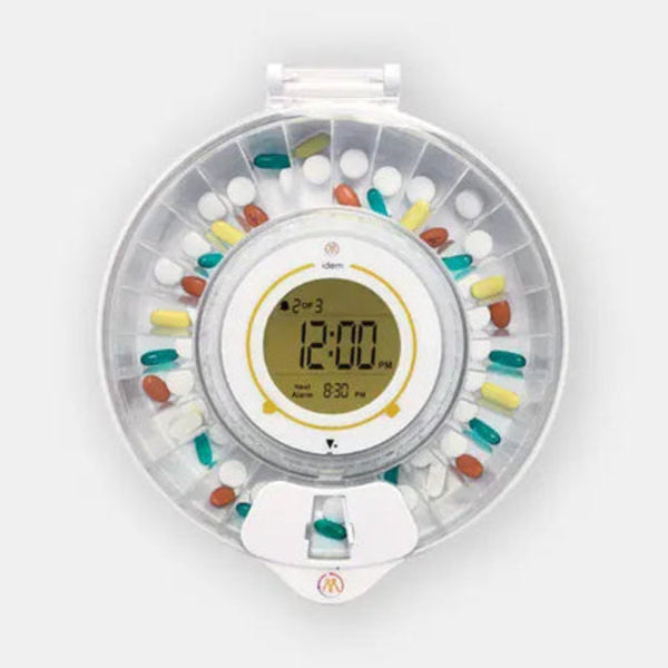 Idem pill dispenser with clear lid full of medication ona white background.