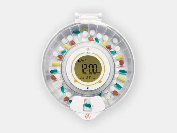 Idem pill dispenser with clear lid full of medicationb on a white background.