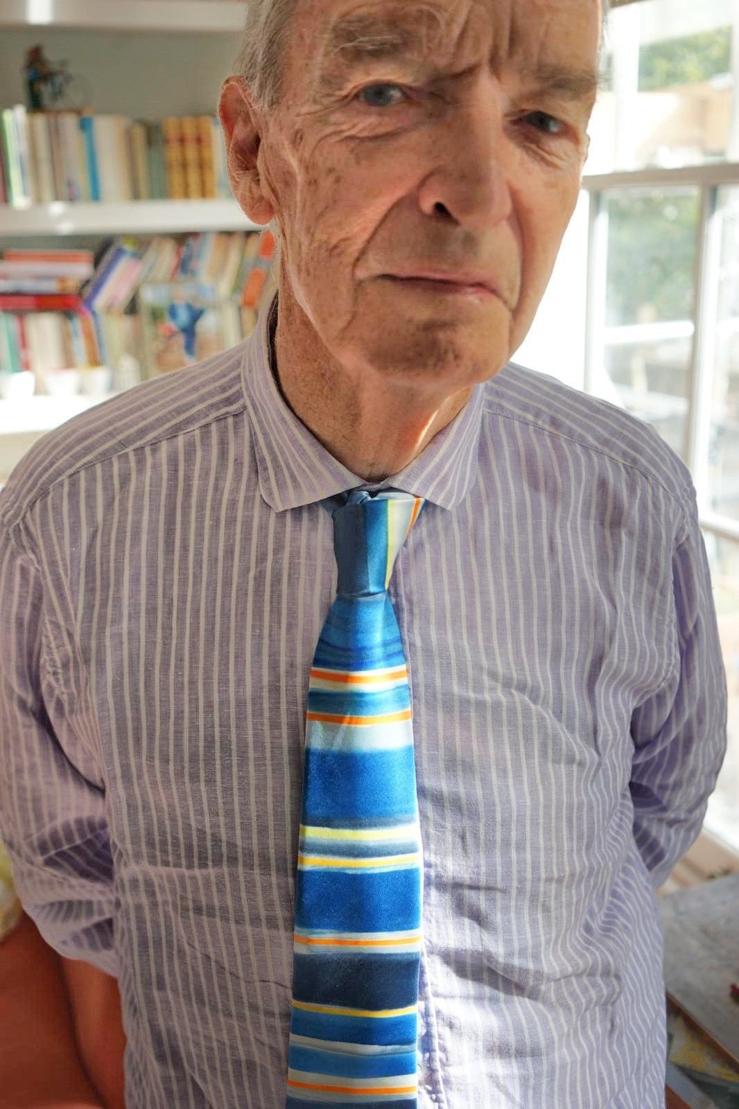 Journalist and TV show presenter Jon Snow wearing the silk tie designed in collaboration with Jon by Victoria Richards - wearing a blue and white striped shirt and the Alzheimer's Society blue, yellow and white tie.