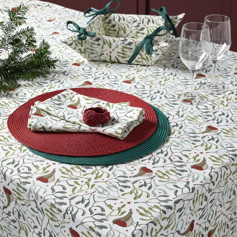 Robins and green mistletoe design on white cloth as well as red and green placemats, glasses and bread basket