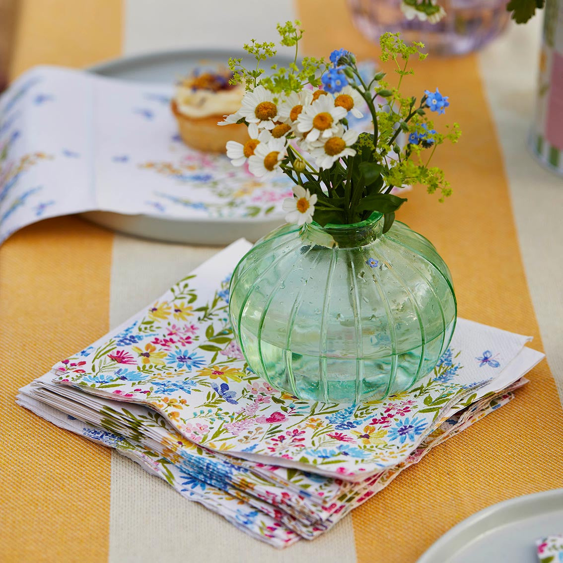 lots of floral napkins under a vase of flowers on a table