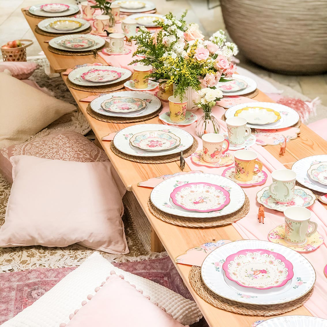 Garden floor table with vintage tableware and cushions on the floor