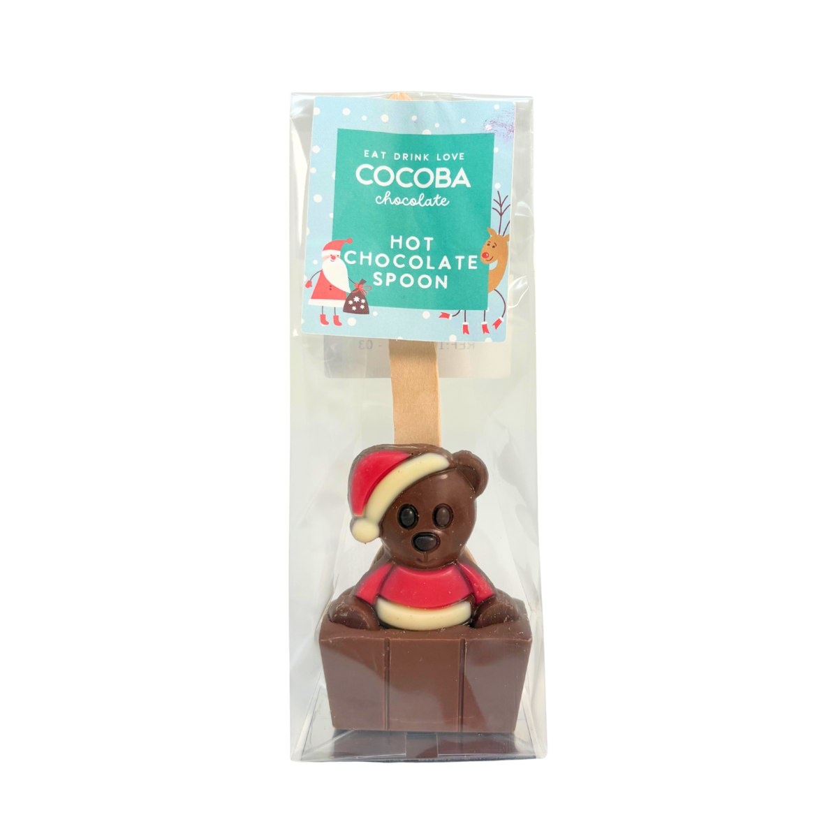 A packaged chocolate hot chocolate spoon featuring a brown chocolate teddy bear wearing a red Santa hat and red sweater, seated in a small brown chocolate cube. The item is enclosed in a clear plastic bag with a printed header card reading 'COCOBA chocolate HOT CHOCOLATE SPOON'.