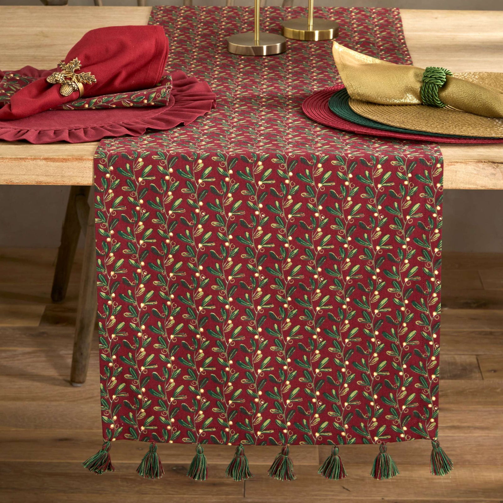 Mistletoe pattern table runner on a table with candles and napkins.