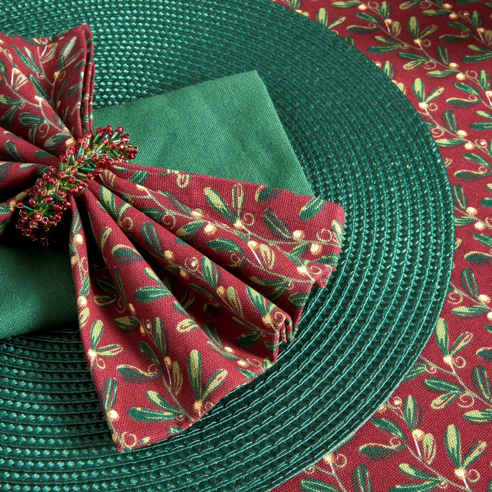 Mistletoe pattern napkin on a green place setting close up.