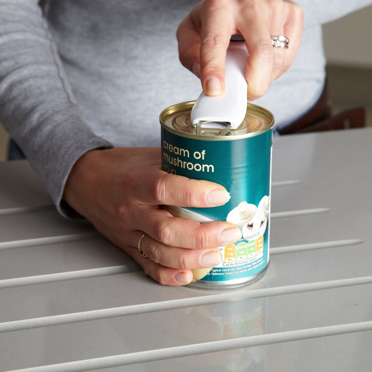 Hand close-up using a gadget to open a ring pull easily on a can of soup
