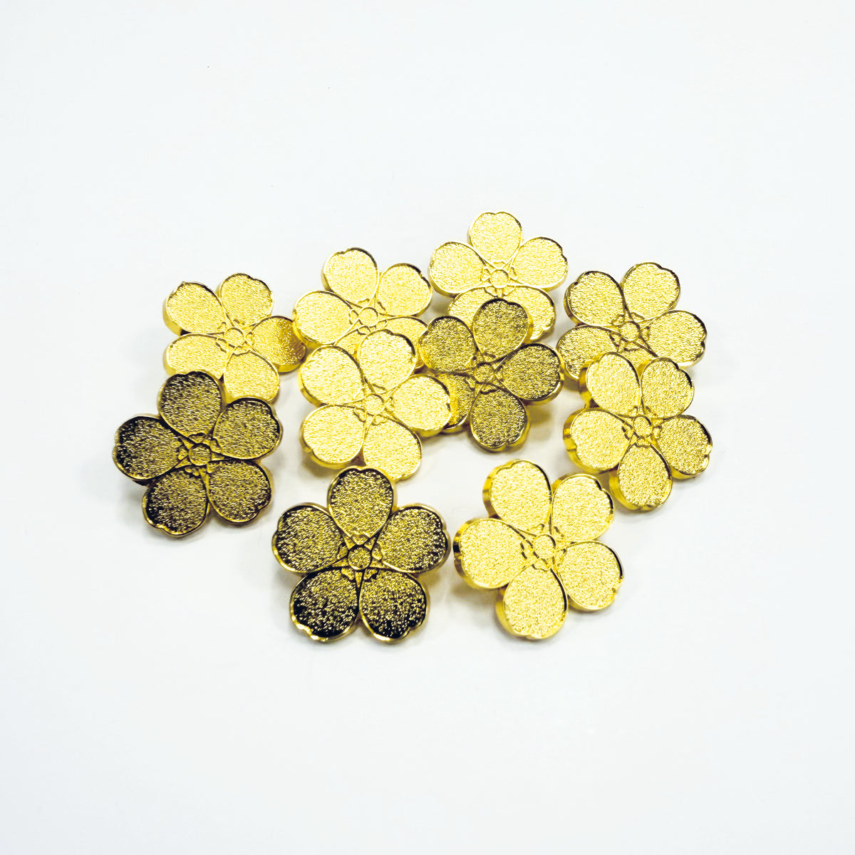 10 gold forget-me-not metal pin badges on a white background