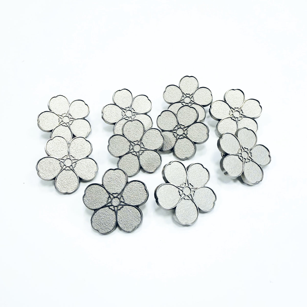 10 Silver forget-me-not pin badges on a white background