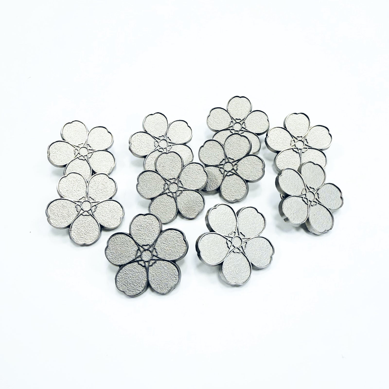 10 Silver forget-me-not pin badges on a white background
