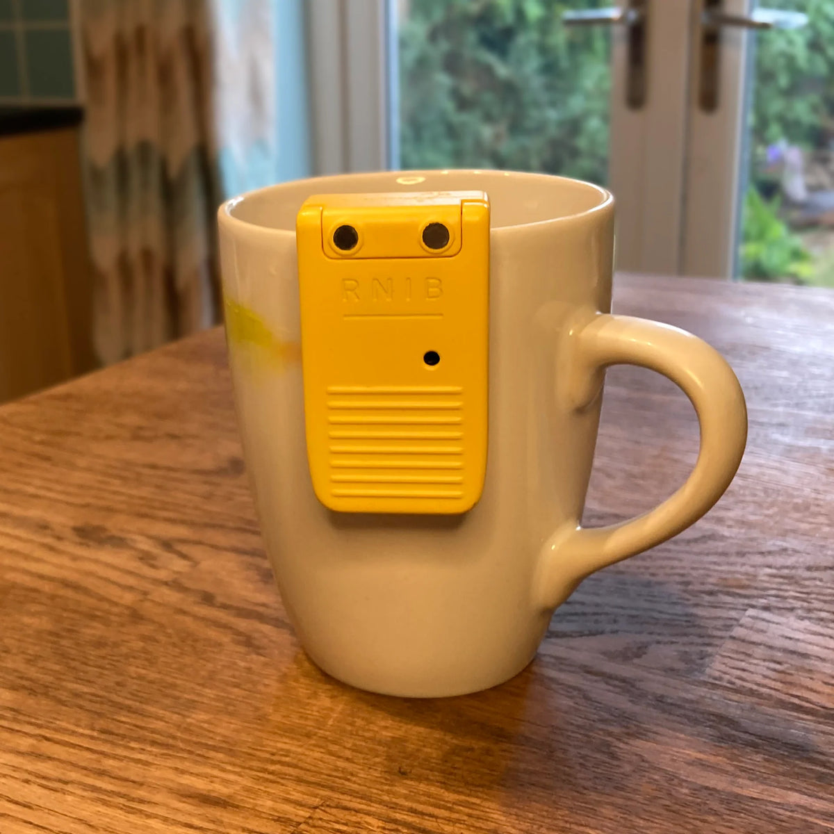 White mug with a yellow liquid level indicator on it, placed on a wooden surface