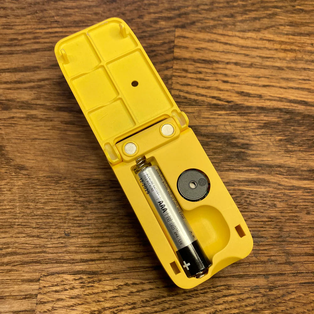 Yellow battery holder with a AAA battery on a wooden surface