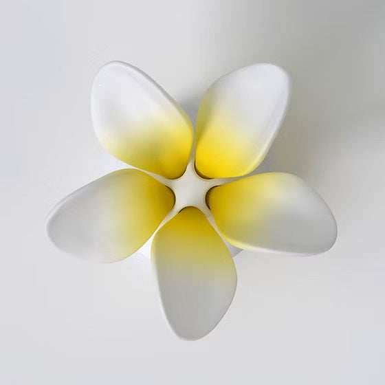 A completed frangipani flower puzzle with five hand-painted petals in white, yellow, and gray colors on a white background.