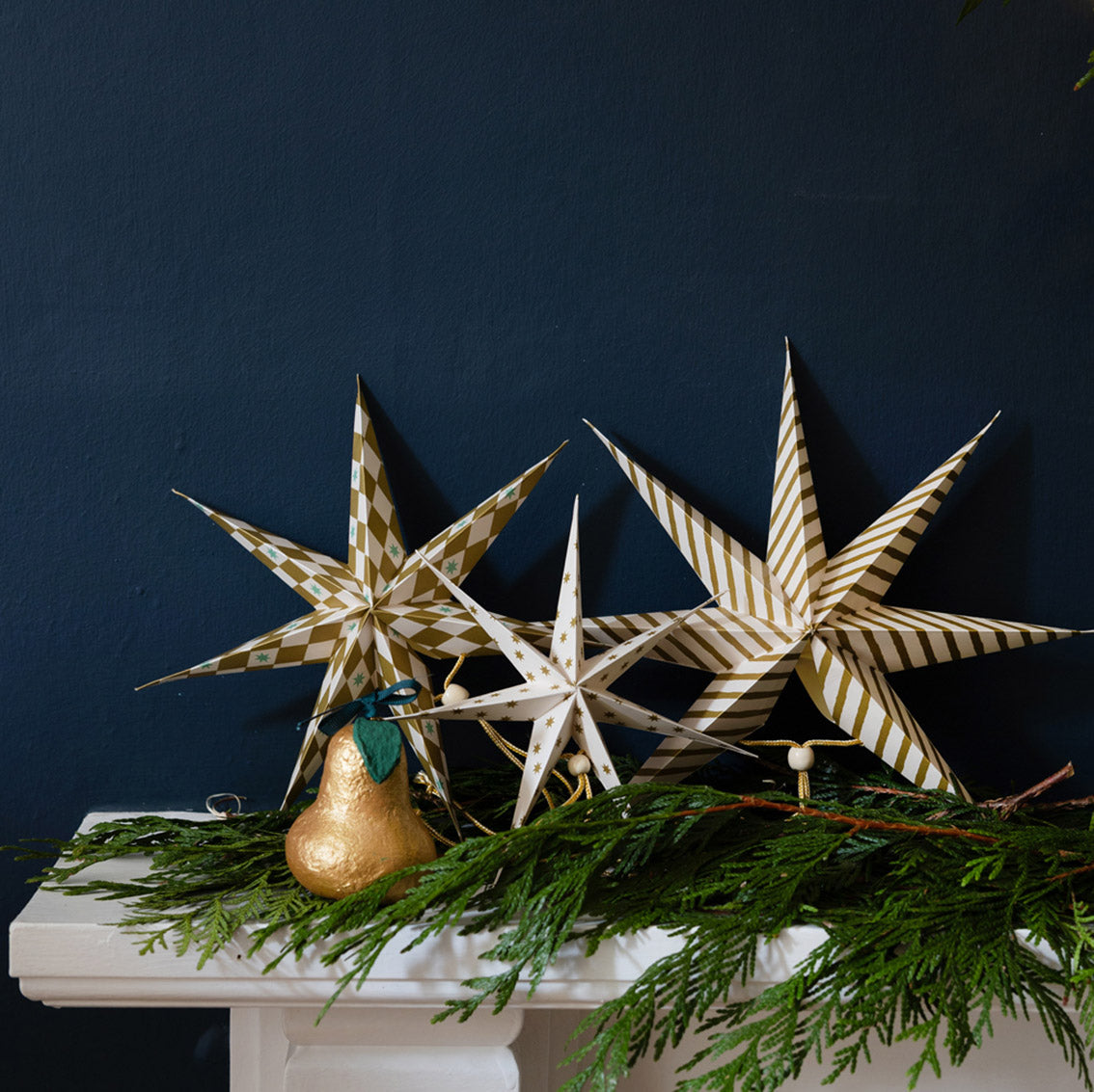 Decorative stars and a gold pear on a white surface with a dark blue background