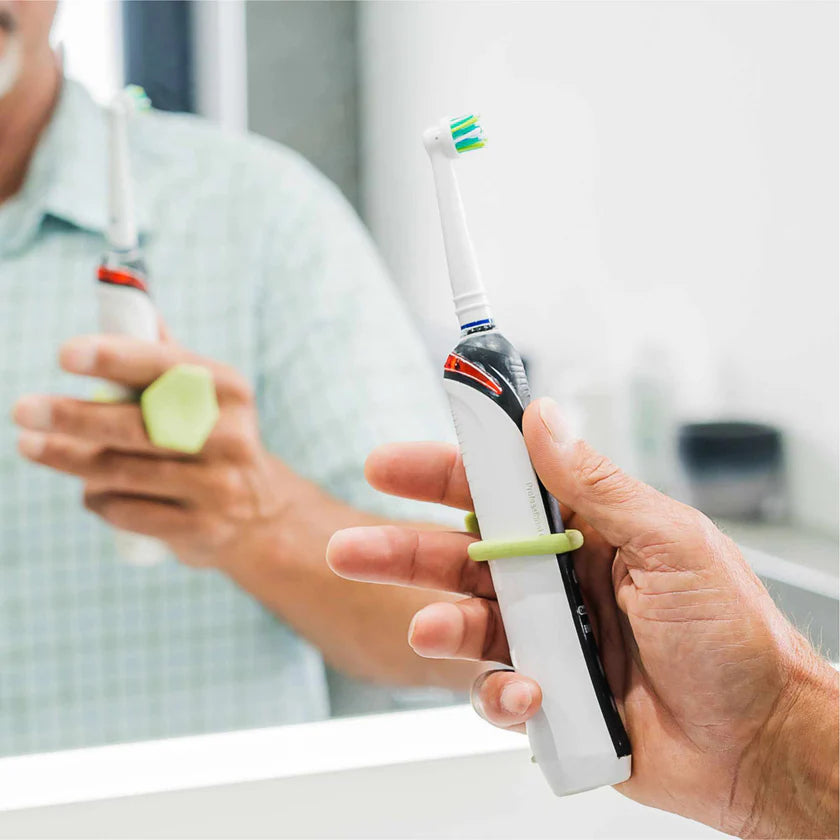 Person holding a toothbrush with a holder in front of a mirror