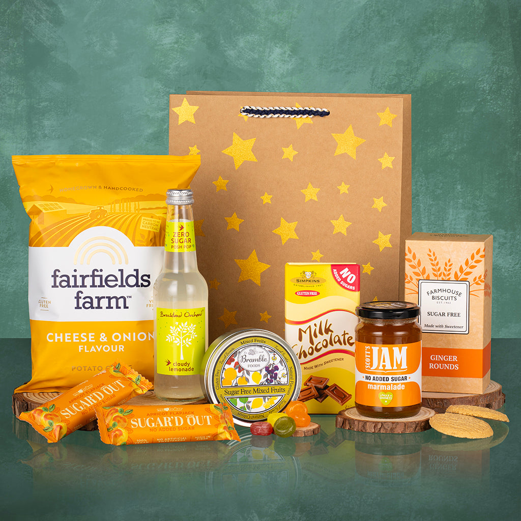 Low sugar themed gift set with gold stars bag, food items, and a bottle of cloudy lemonade.