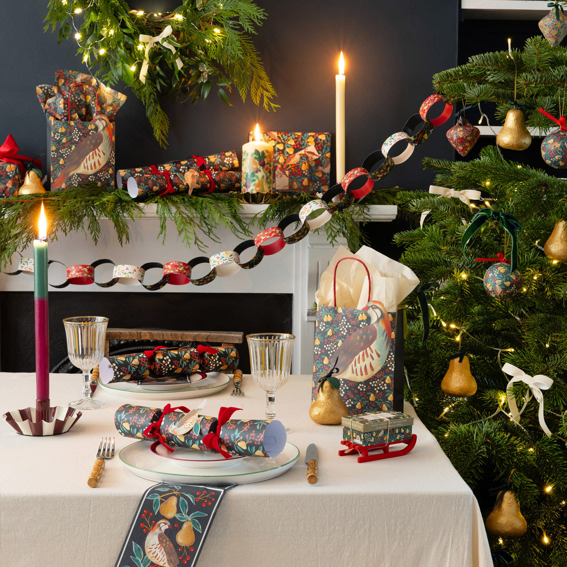 Decorated Christmas table with tree, candles, and gift bags in a festive setting.