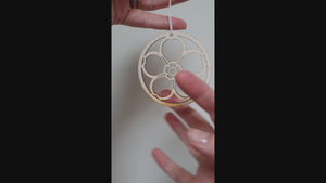 A video showing the wooden laser-cut forget-me-not decoration hanging from a white string.