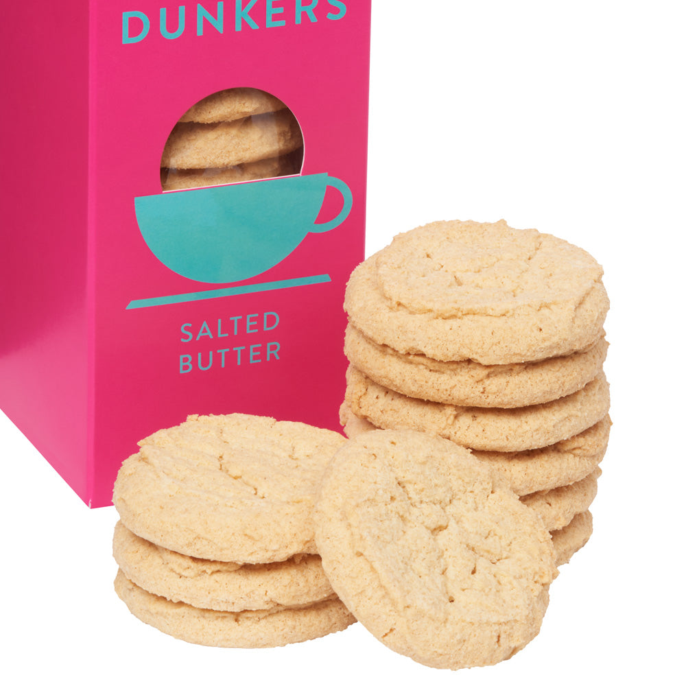 A bright pink box labeled 'DUNKERS' and 'SALTED BUTTER' with a teal cup graphic, shown beside several round butter cookies on a white background.