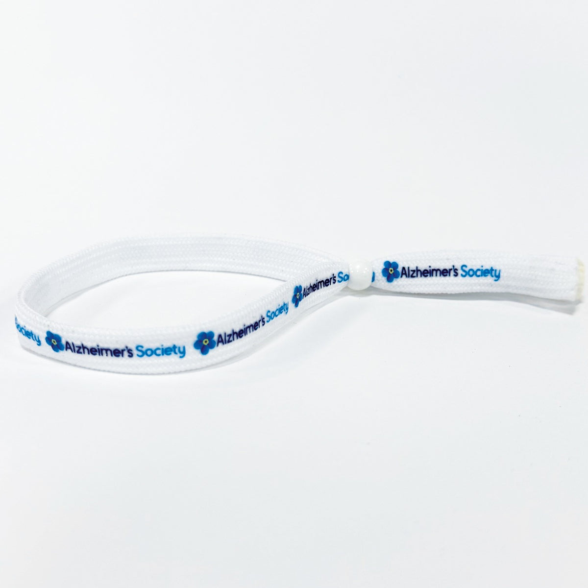 White flat shoelace style fabric wristband in a loop with a white plastic bead sliding closure. Alzheimer's Society logo including the forget-me-not flower is printed several times in full colour on the wristband.